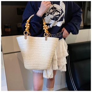 Detailed shot of handmade straw tote bag featuring decorative wooden bead handles