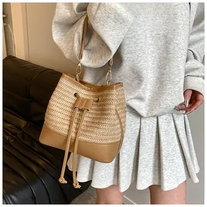 Detail of the woven straw texture and brown leather drawstring closure on a bucket bag