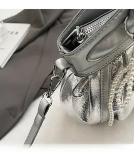 Detail of silver metallic bag featuring a pearl chain strap and high-quality hardware