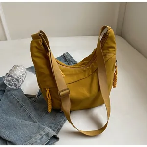 Close-up of yellow half-moon hobo bag with woven zipper pull and wide shoulder strap