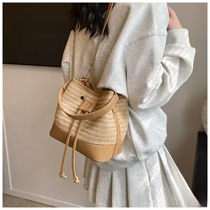 Detail of straw bucket bag showing woven texture and brown PU leather straps