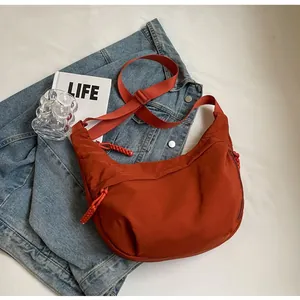 Detail of burnt orange nylon crescent bag with woven zipper and adjustable strap