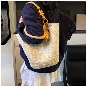 Detail of hand-woven straw tote with unique wooden bead handles for beach vacation style