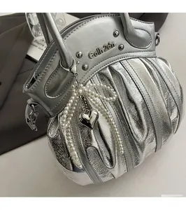 Macro detail of silver pleated handbag with pearl bow charm and heart-shaped pendant