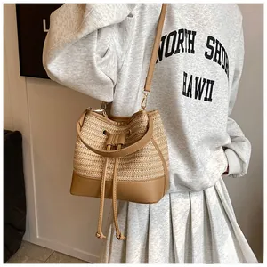 Detail of straw bucket bag featuring a drawstring closure and brown leather trim