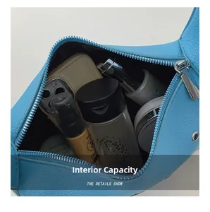 Internal view of blue textured leather shoulder bag showing capacity for cosmetics and phone