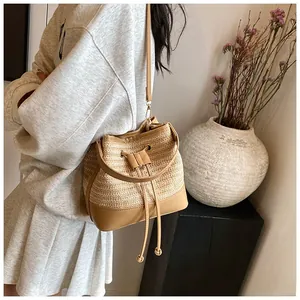 Detail of hand-woven straw bucket bag featuring premium leather trim and drawstring closure