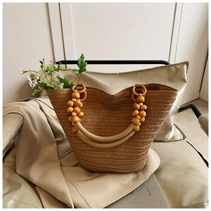 Detail of wooden bead handles and woven rope texture on a natural straw tote bag
