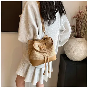 Detail of straw woven bucket bag with brown leather drawstring and shoulder strap