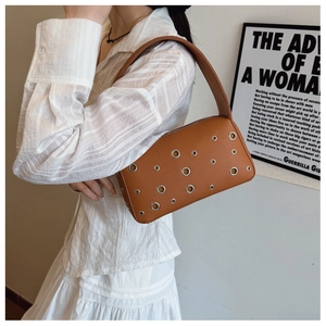 Detail of caramel brown pebbled leather shoulder bag with decorative silver metal eyelets