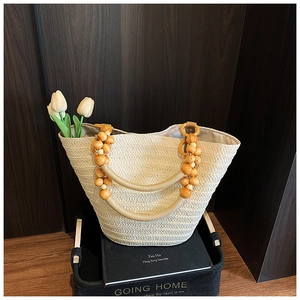 Detail of hand-woven straw tote with elegant yellow wooden bead handles and interior lining