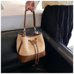 Detailed shot of handmade straw bucket bag with brown leather handles and drawstring