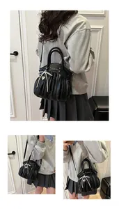 Detail of black pleated bag with pearl bow, heart pendant and metallic logo finish