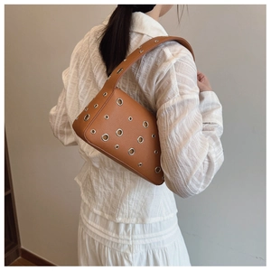 Brown leather underarm bag with decorative silver grommets and punk style shoulder strap