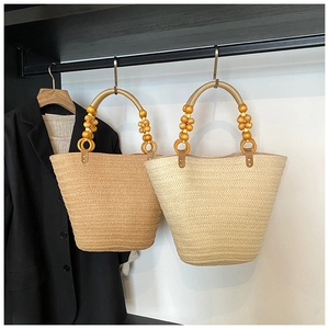 Detail of straw tote bag showing hand-woven texture and unique round wooden bead handle