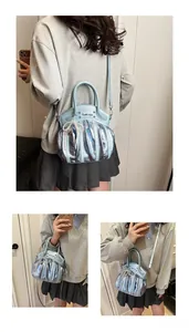 Detail of light blue metallic pleated handbag with pearl charm and logo texture