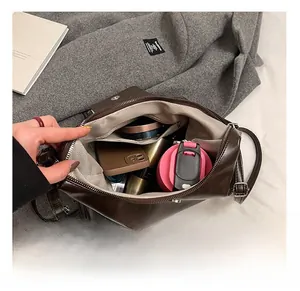 Spacious interior of dark brown leather crossbody bag with items and herringbone lining