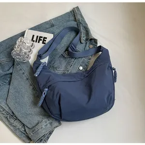 Detail of navy blue hobo bag with a distinctive woven rope zipper pull on denim