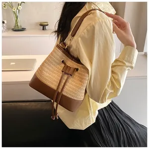 Detail of straw and brown leather bucket bag showing drawstring closure on female model