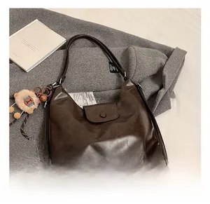 Detail of dark brown Hobo bag with lion plush pendant on grey wool background