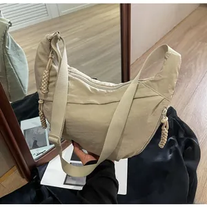 Detail of beige nylon crescent bag with adjustable strap and braided zipper pull
