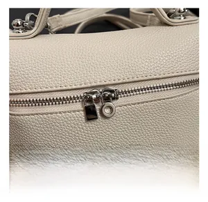 Detailed close-up of premium lychee leather texture and silver hardware zipper on bag