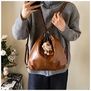 Close-up of vintage brown leather backpack with plush ball charm in a warm festive setting