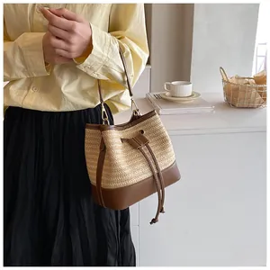 Detail of hand-woven straw bucket bag with leather drawstring and gold-tone hardware