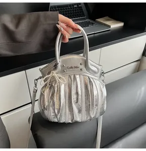 Detail of silver metallic handbag with pleats and pearl bow charm in an office setting