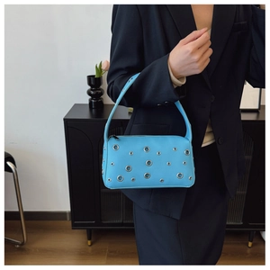 Detail of light blue lychee pattern leather shoulder bag with silver metal grommets