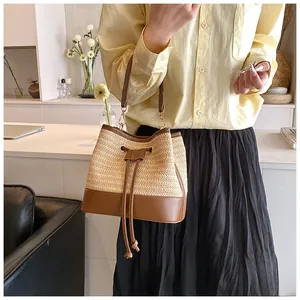 Detail shot of hand-held woven bucket bag with cream fabric and brown leather accents