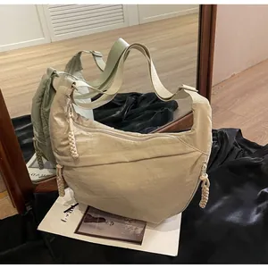 Detail of light beige crescent bag showing woven zipper pulls and wrinkled nylon texture