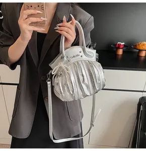Detail of silver metallic pleated handbag with pearl charm and detachable strap