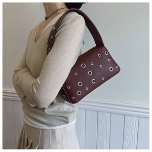 Detail view of burgundy underarm bag with litchi texture and silver metal eyelets