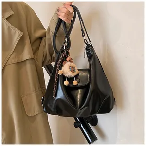 Close-up of black PU leather hobo bag with silver zipper and plush lion charm