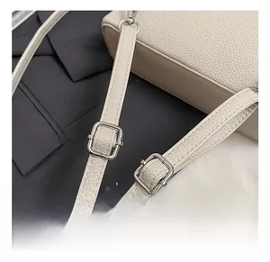 Detail of adjustable cream lychee texture straps with silver metal buckles on a chic bag