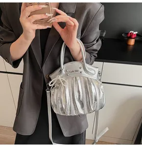 Detail of silver pleated handbag with gothic logo, metal studs and pearl bow charm