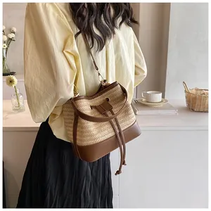 Detail of hand-woven straw bucket bag with brown leather trim and drawstring closure