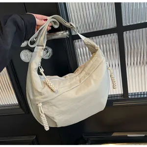 Detail view of beige crescent bag with wrinkled nylon texture and braided zipper puller