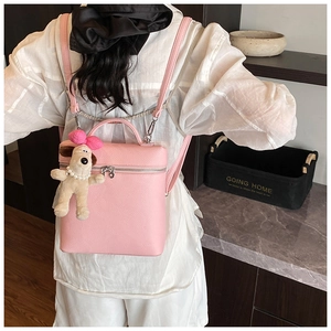 Pink lychee texture backpack shown with cute puppy plush charm and silver zippers