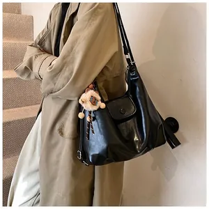 Detail of black glossy PU leather tote bag with a cute plush charm and flap closure