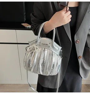 Detailed view of silver pleated leather handbag with pearl bow charm and metal logo