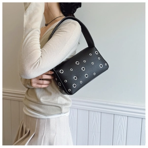 Detail of black underarm bag featuring textured leather and silver metal eyelets