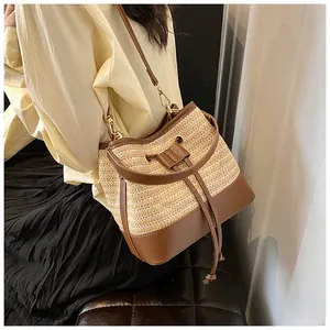 Close-up of woven straw bucket bag with leather trim and drawstring closure detail