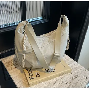 Detail of light beige crescent bag showing pleated texture and adjustable buckle strap