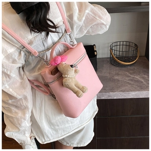 Close-up of pink litchi grain leather backpack with cute plush dog pendant detail