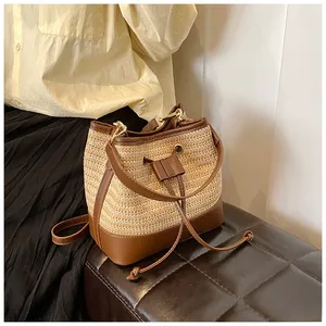 Detail of woven straw bucket bag with brown leather trim and drawstring closure