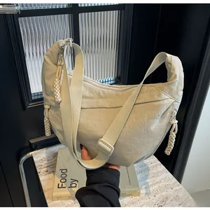 Detail of cream nylon dumpling bag featuring textured pleats and woven knot zipper puller