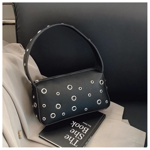 Close-up of black lychee leather underarm bag with decorative silver metal rings