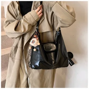Black leather hobo shoulder bag with a cute lamb plush charm detail shown on model